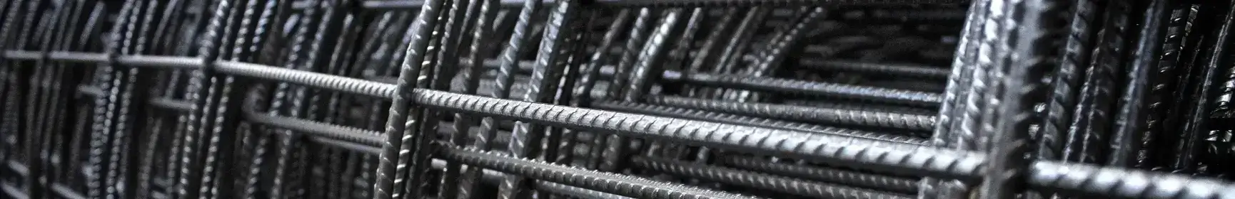Primer plano de barras de acero estructural entrelazadas, formando una malla metálica utilizada en construcción.